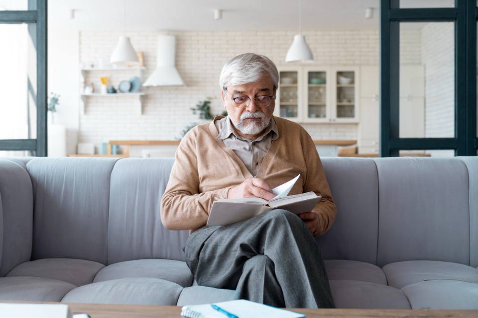 An older man reading at home on his sofa
