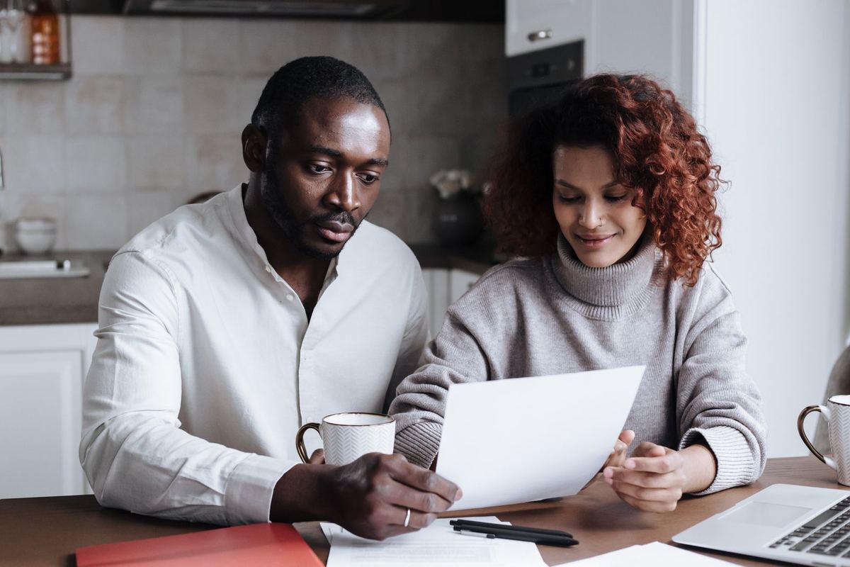 A couple reading paperwork together at their kitchen table